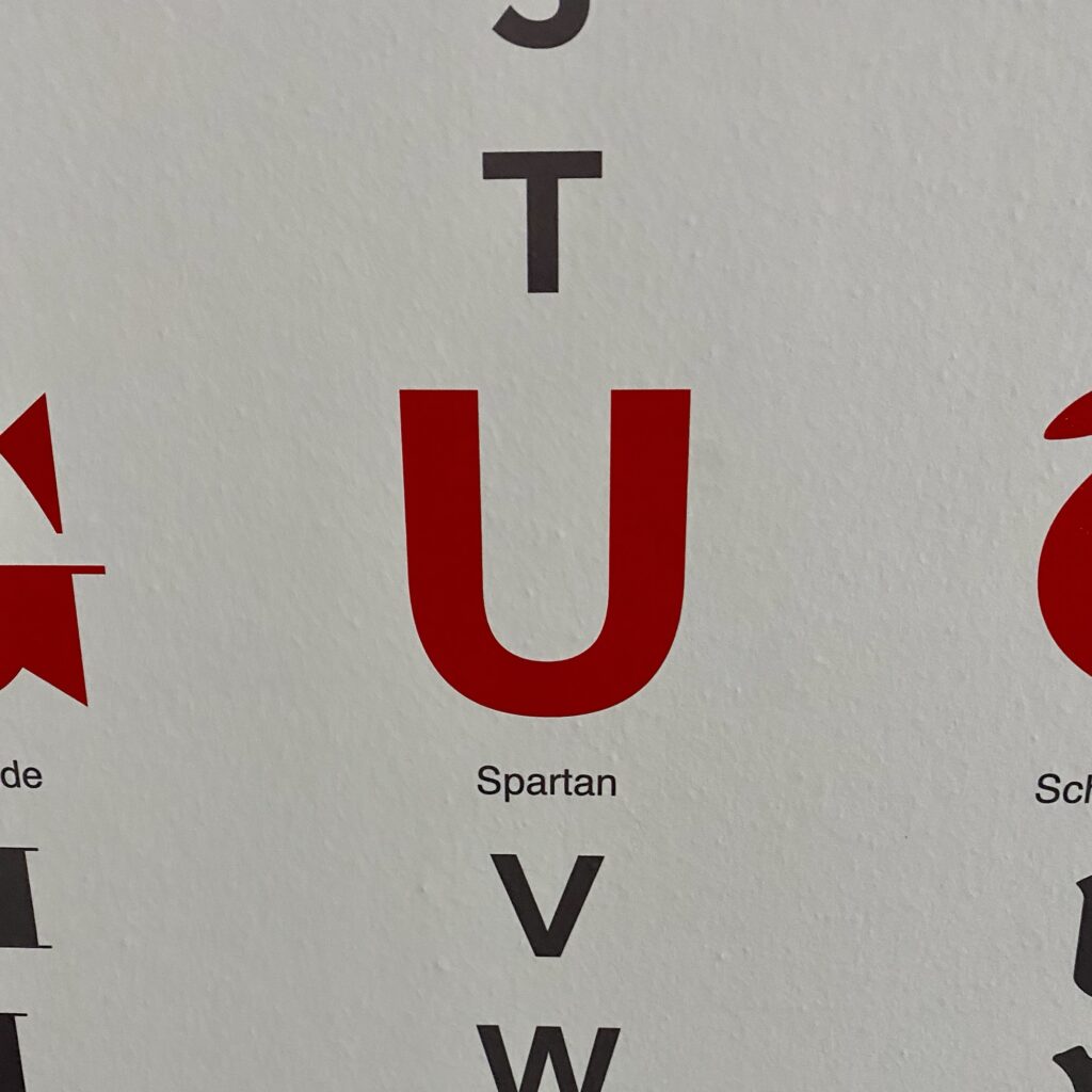 Red and grey letters displayed on a white background, including the letter U and the word 'Spartan'.