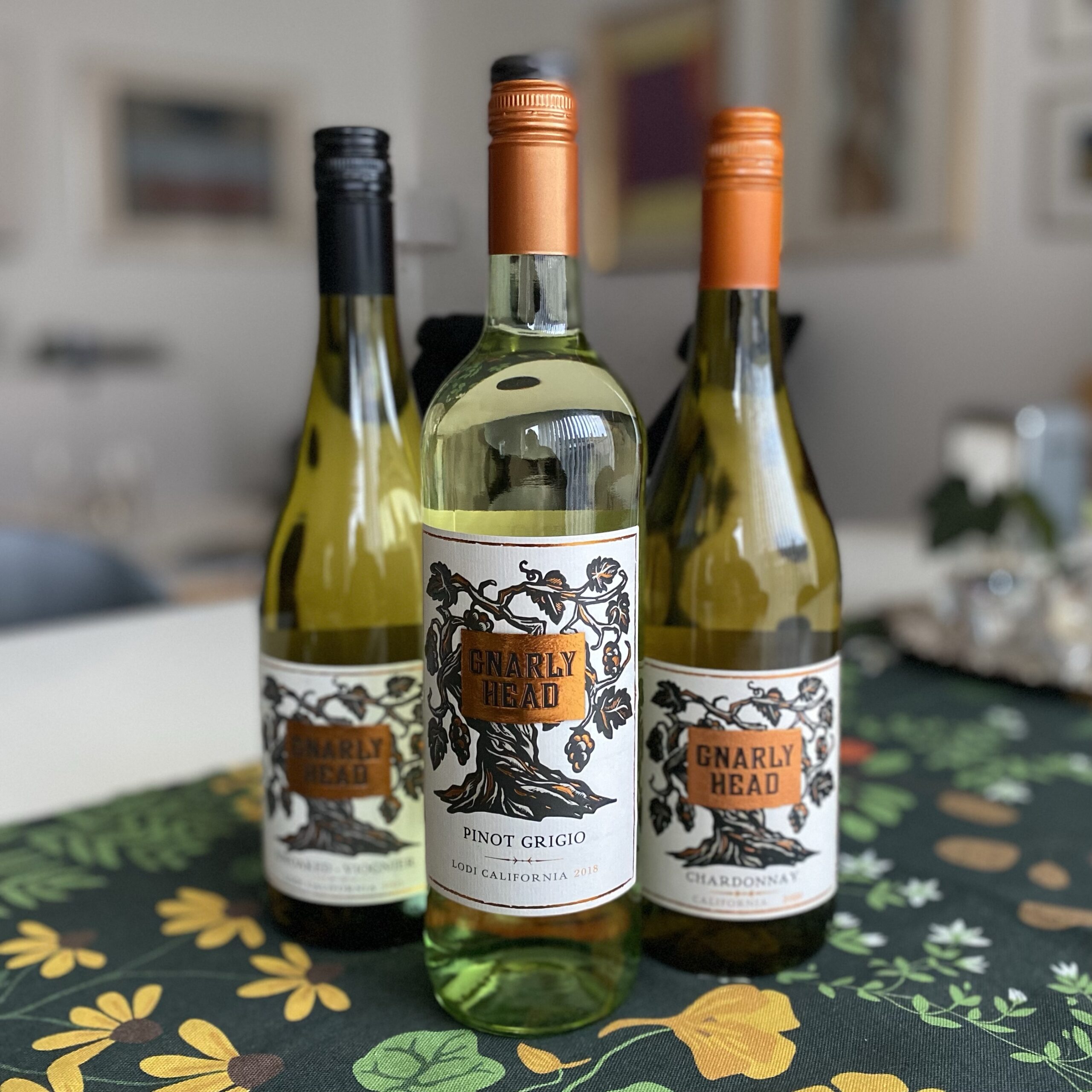 Three bottles of Gnarly Head wine including Pinot Grigio and Chardonnay, displayed on a table.