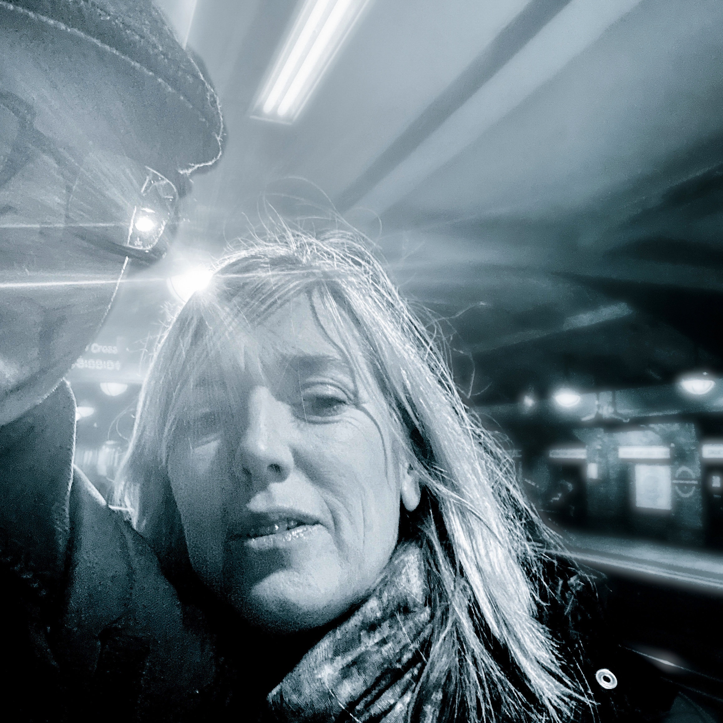 A couple standing close together in a dimly lit station, with light flares creating a dramatic effect.