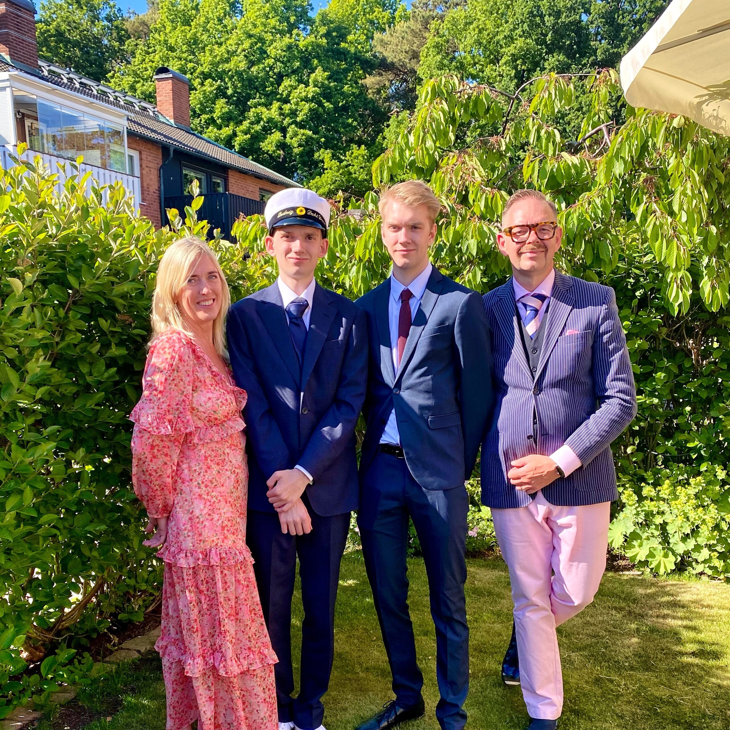 Family portrait featuring four individuals dressed in formal attire, celebrating a graduation event outdoors.