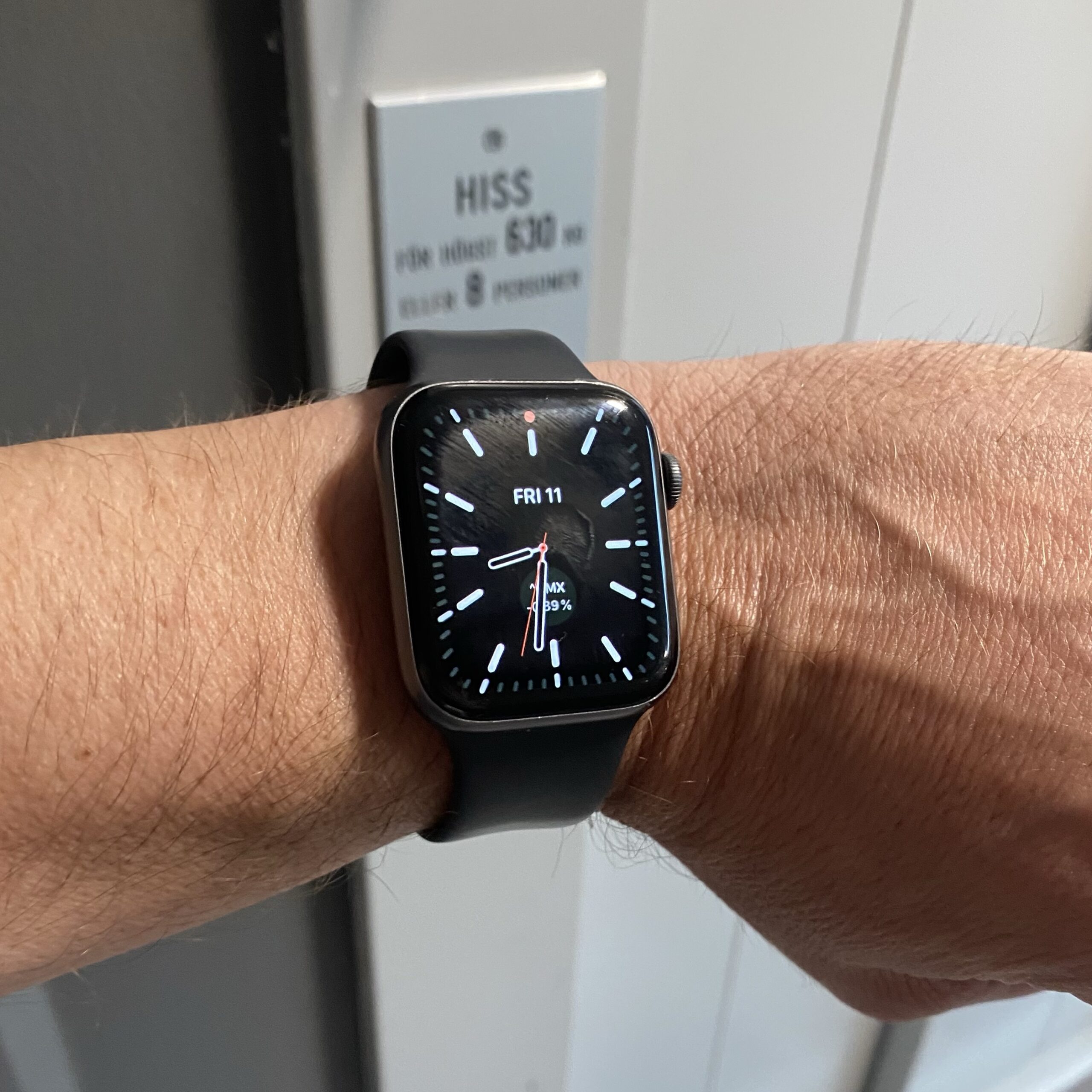 Smartwatch displaying the date and time on a wrist, with a black strap and a minimalistic design.