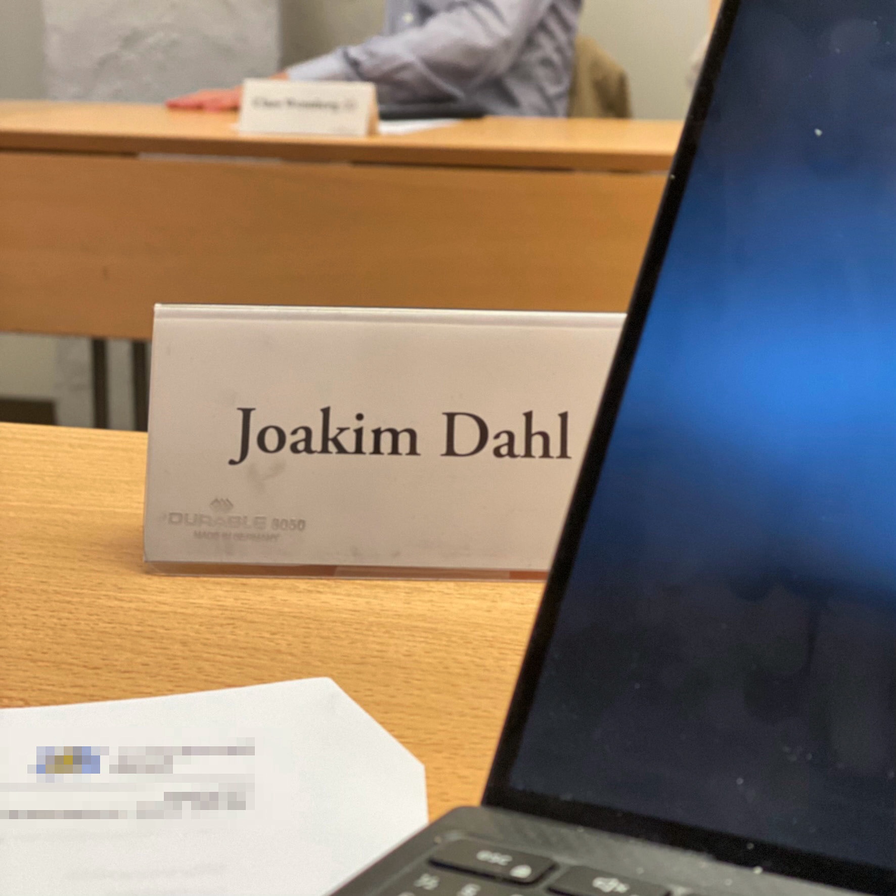 Nameplate displaying 'Joakim Dahl' on a wooden table in a boardroom setting.