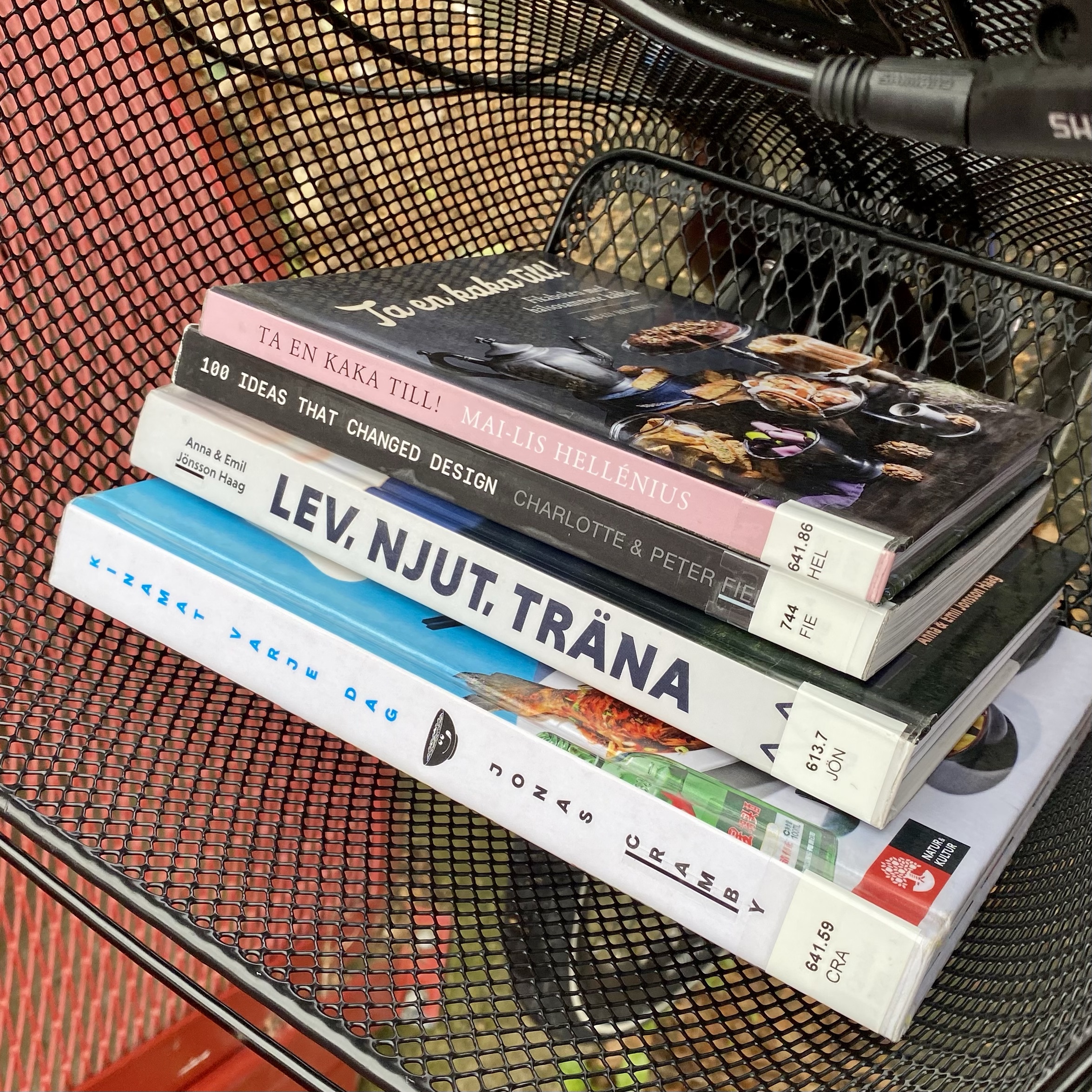 Stack of books in a shopping basket, including titles on design and lifestyle.
