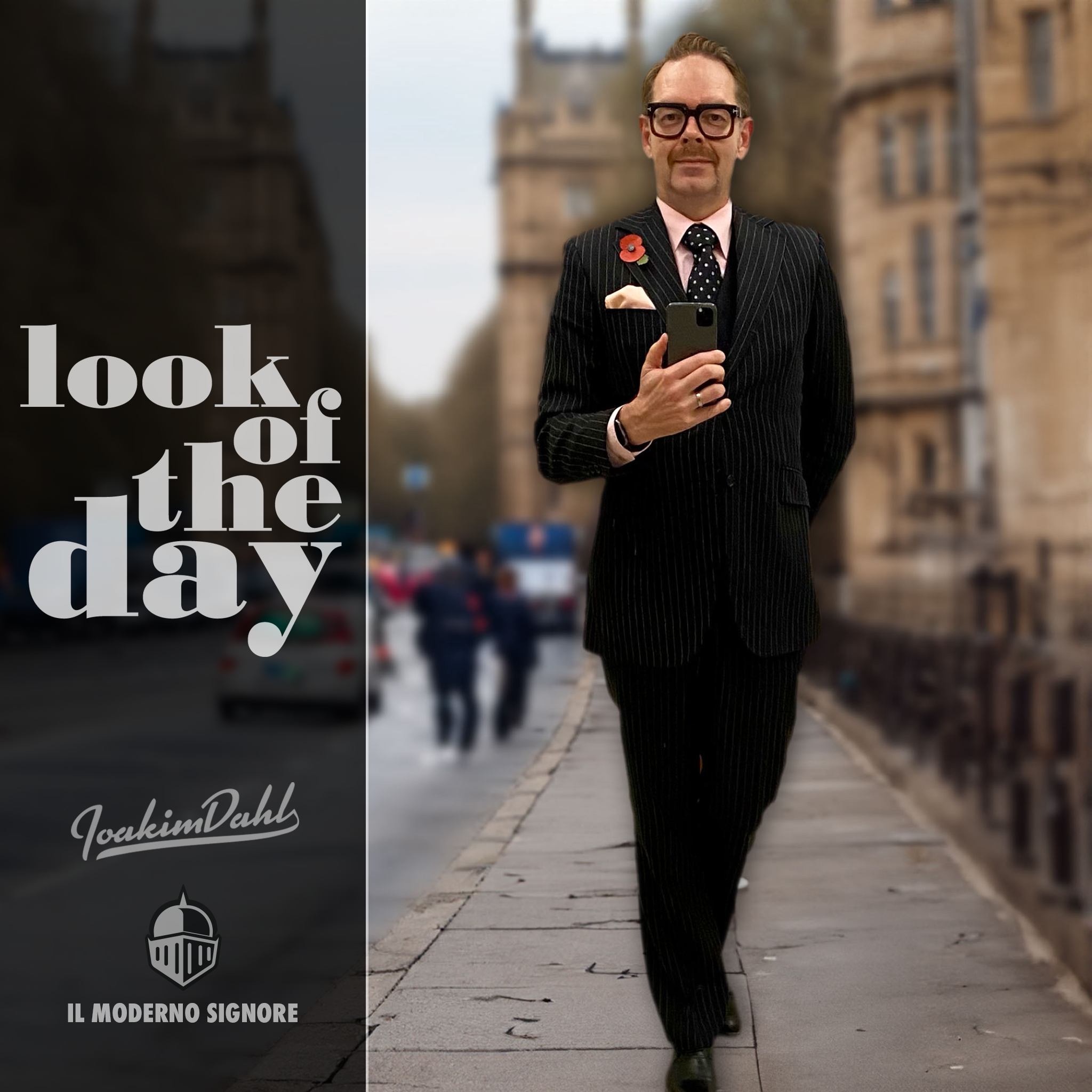 Man in a pinstripe suit holding a smartphone, walking confidently on a city street.