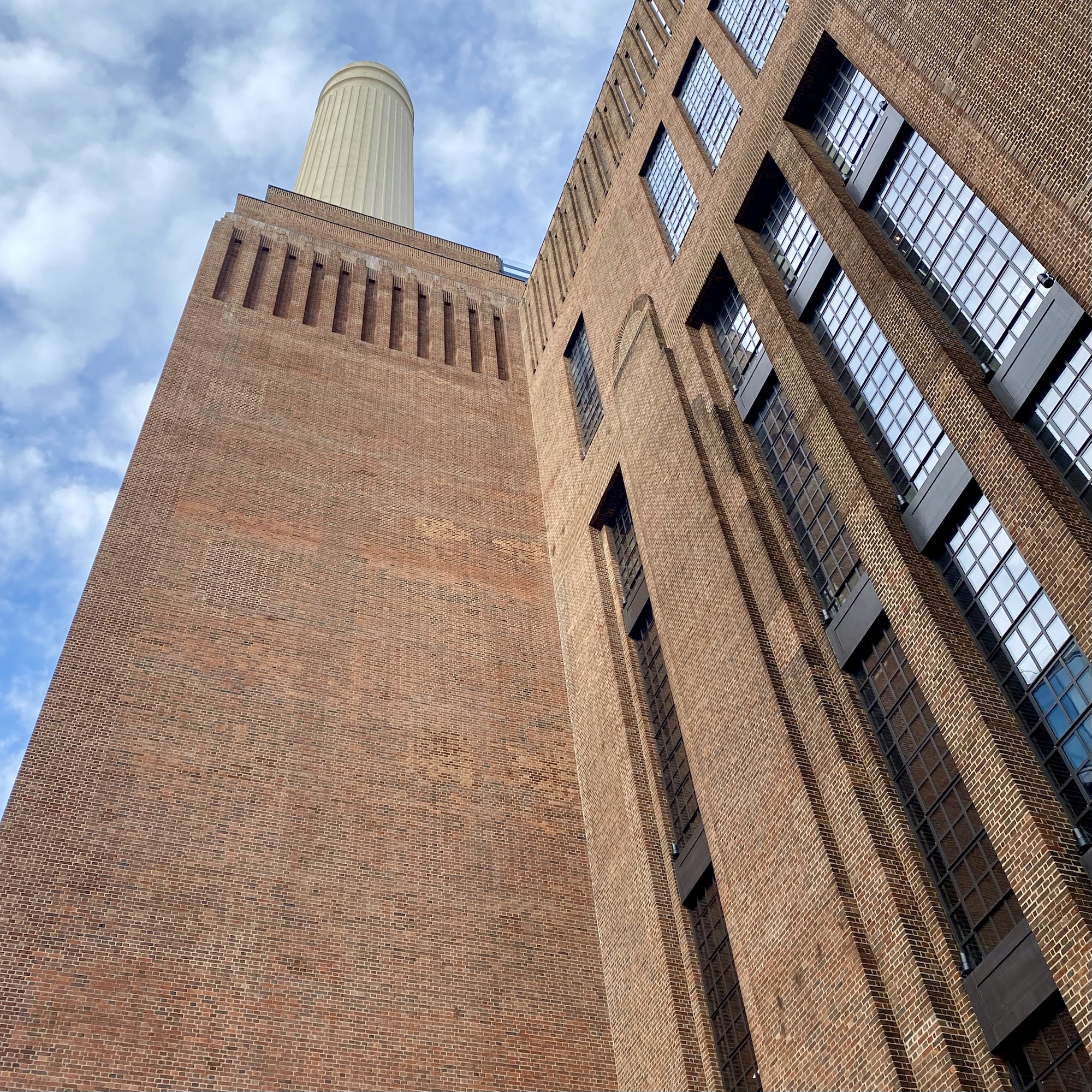 Battersea Power Station, a historic brick building with a tall chimney and large windows.