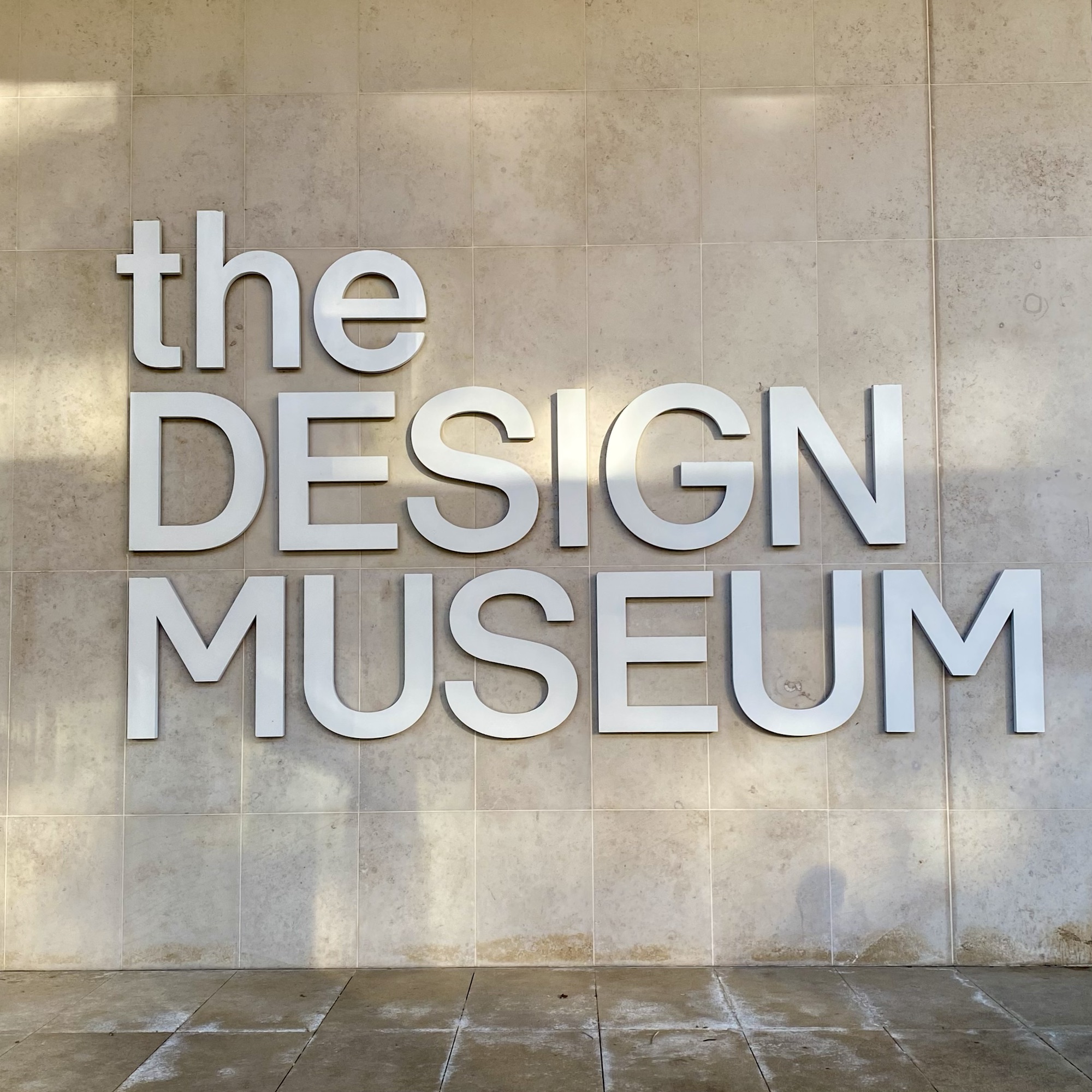 Signage of 'the DESIGN MUSEUM' displayed prominently on a wall with a textured surface.