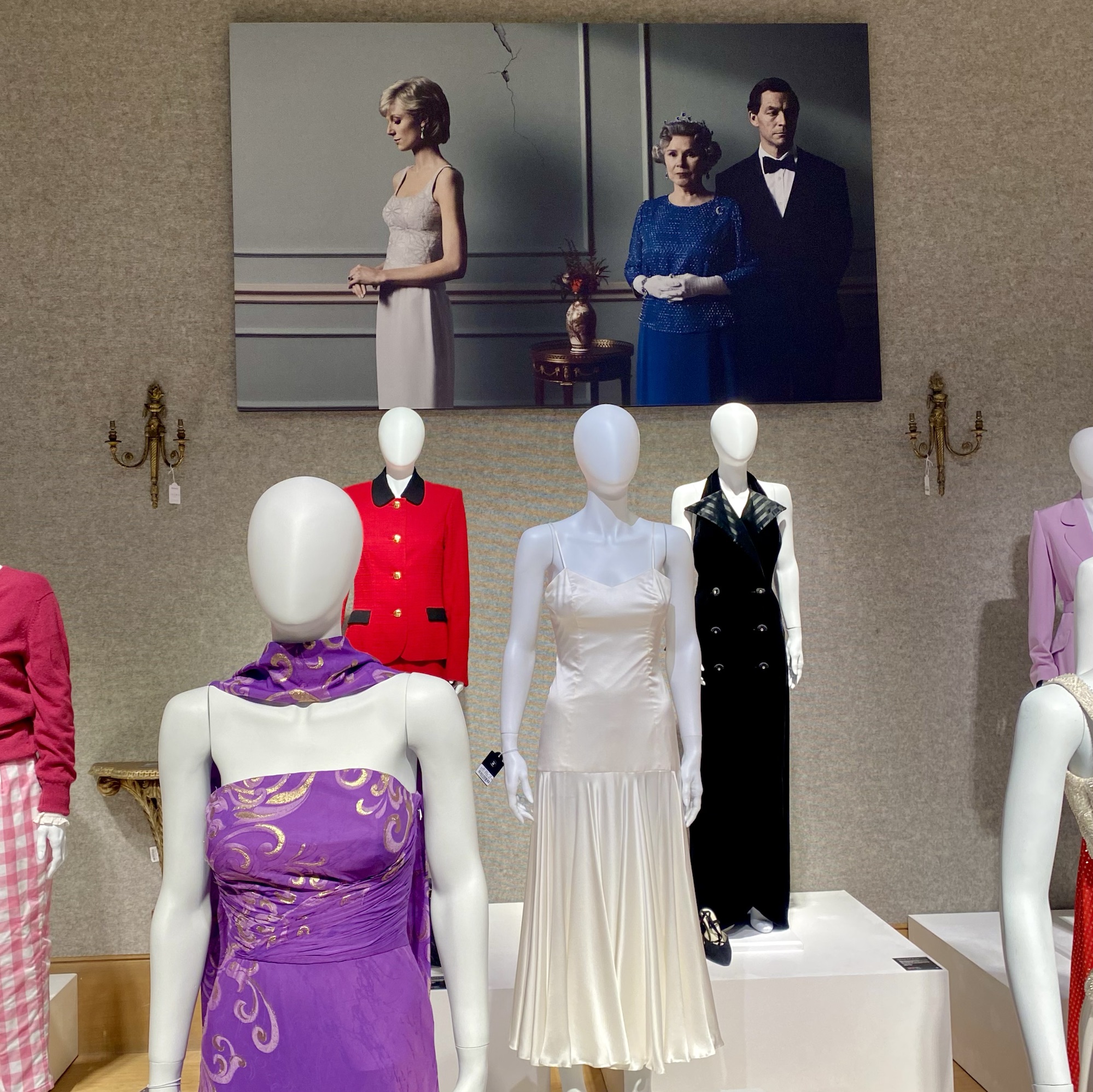 Mannequins displaying various dresses inspired by royal fashion, with a large portrait of Queen Elizabeth II and Princess Diana in the background.