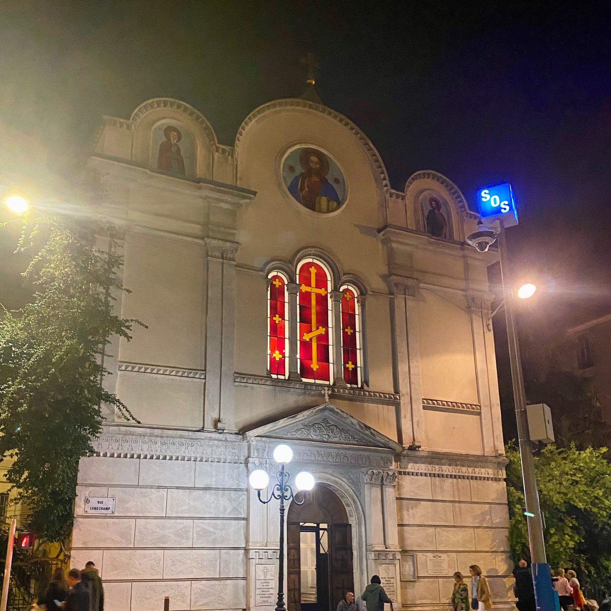 Church building at night with illuminated stained glass windows and exterior lighting.