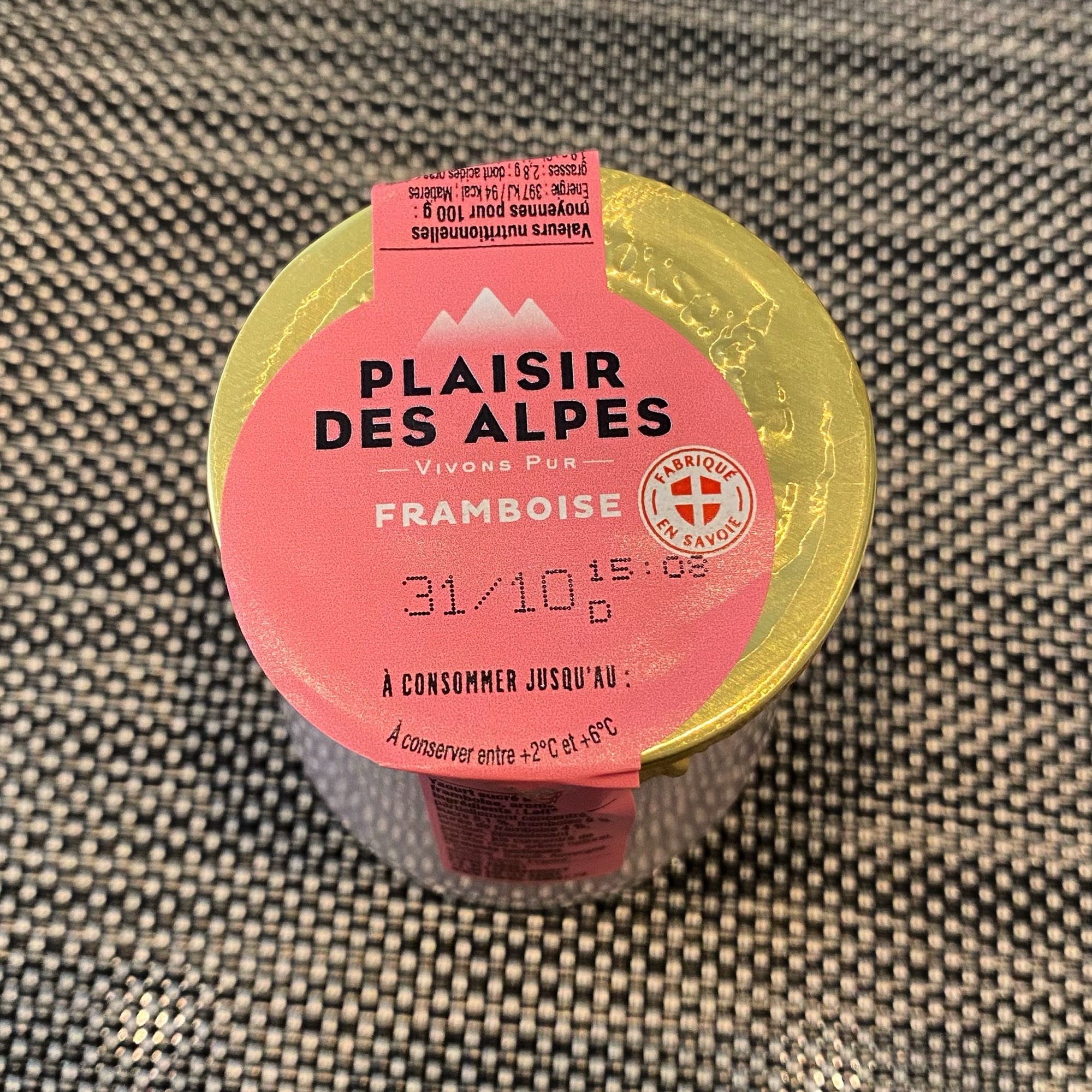 Container of raspberry dessert with a pink label stating 'Plaisir des Alpes' and a best before date.