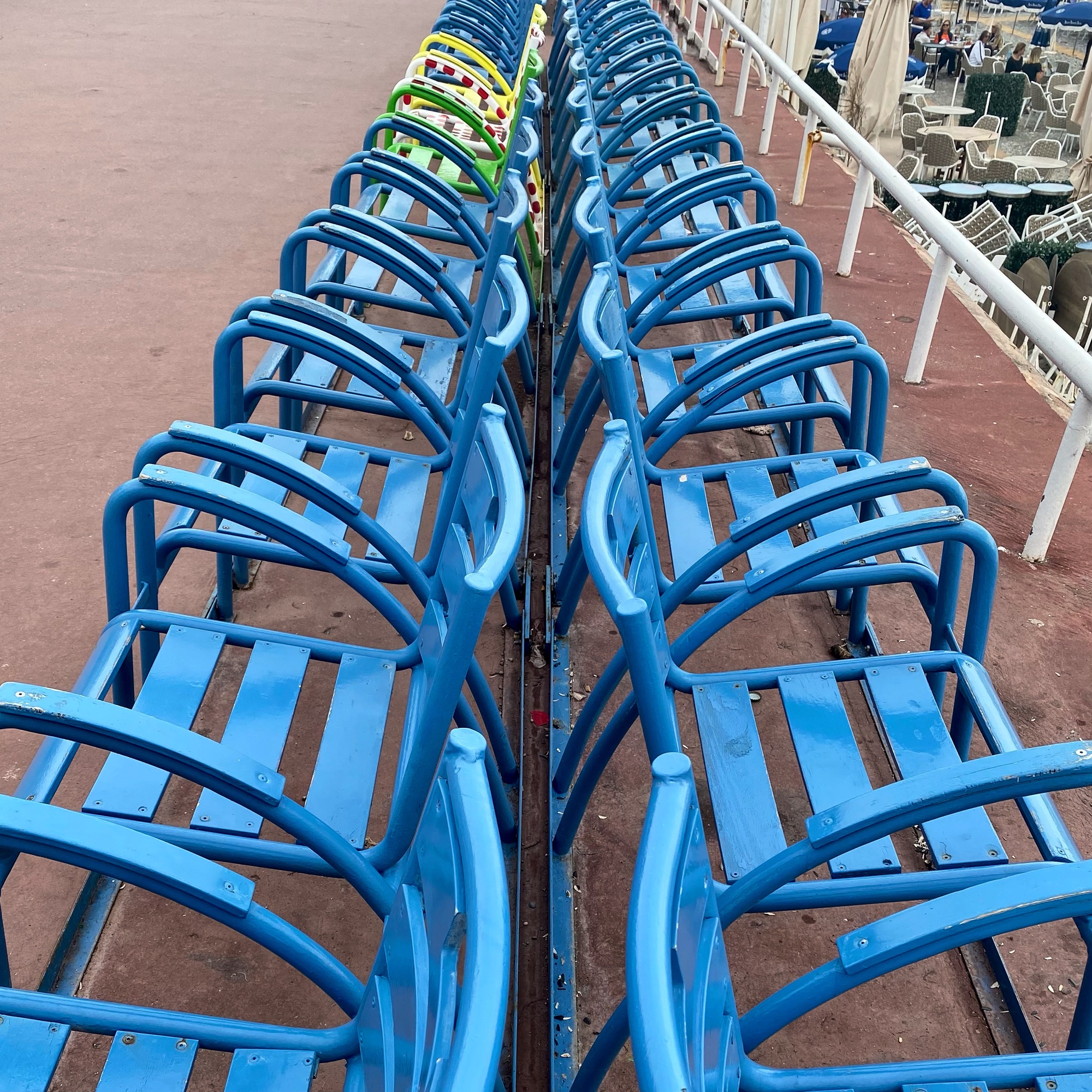 Rows of blue metal chairs arranged in parallel on a deck surface, showcasing a symmetrical pattern.
