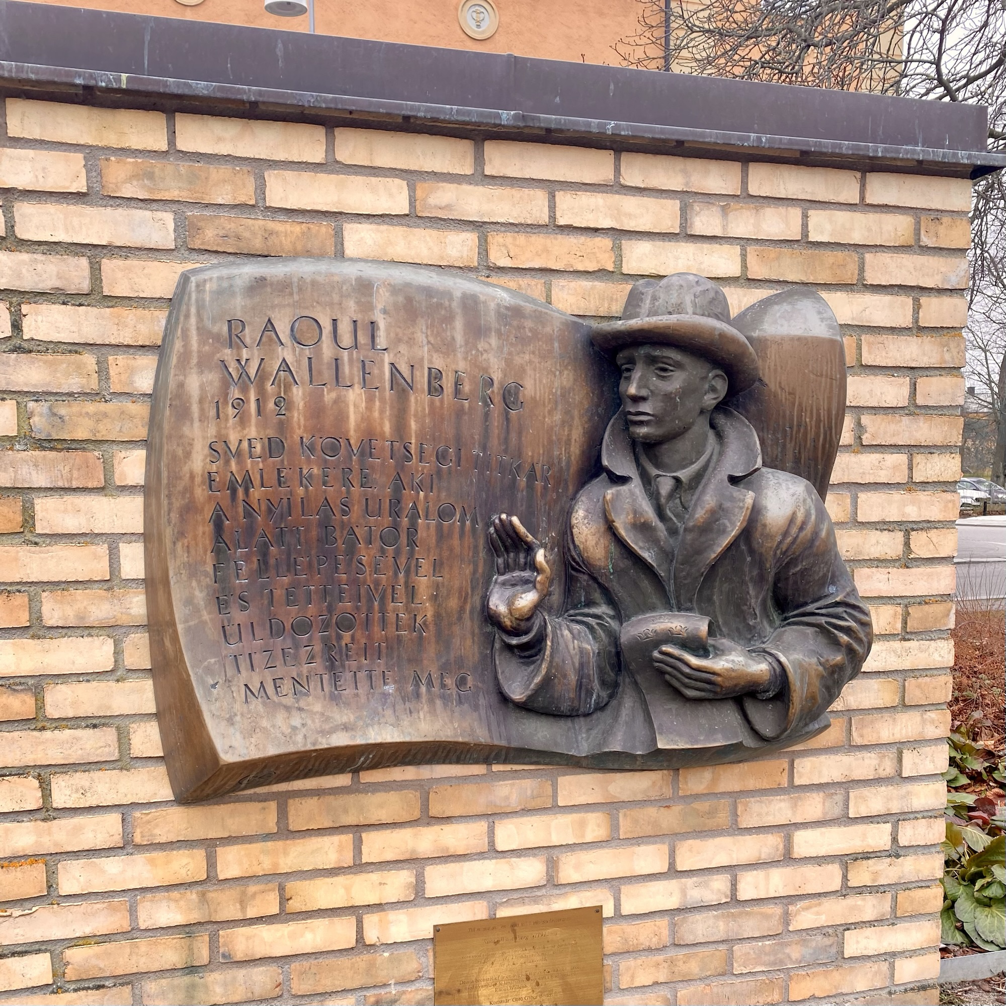 Bronze relief sculpture of Raoul Wallenberg, depicting him in a hat and coat with an outstretched hand.