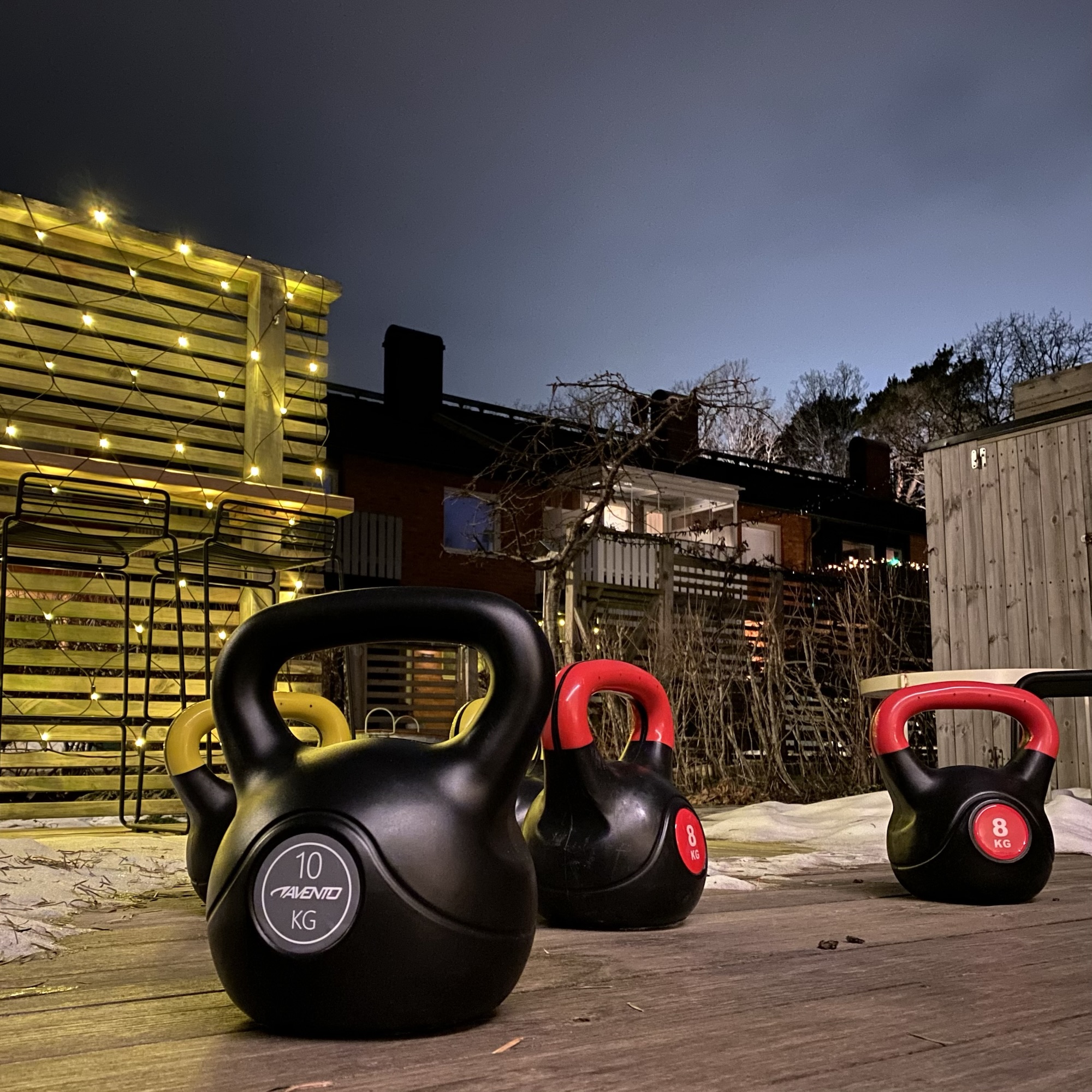 Set of kettlebells in black, red, and yellow, with weights of 8kg and 10kg, arranged on a wooden surface.