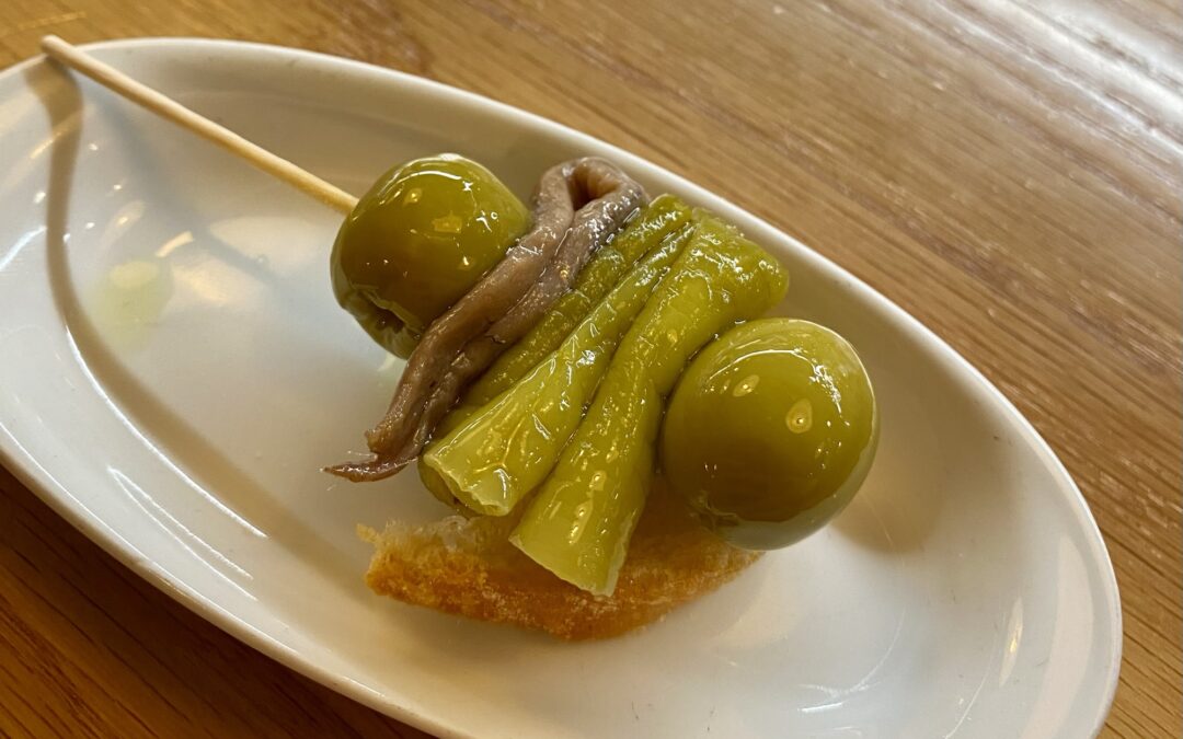 By skewering green olives, salted anchovies and pickled guindilla peppers