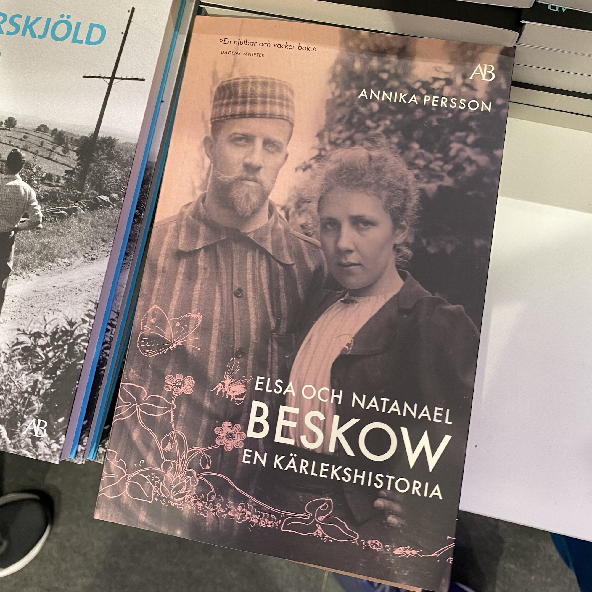 A book cover shows Annika Persson’s portraits of Elsa and Natanael Beskow beneath the Swedish title “En kärlekshistoria”.