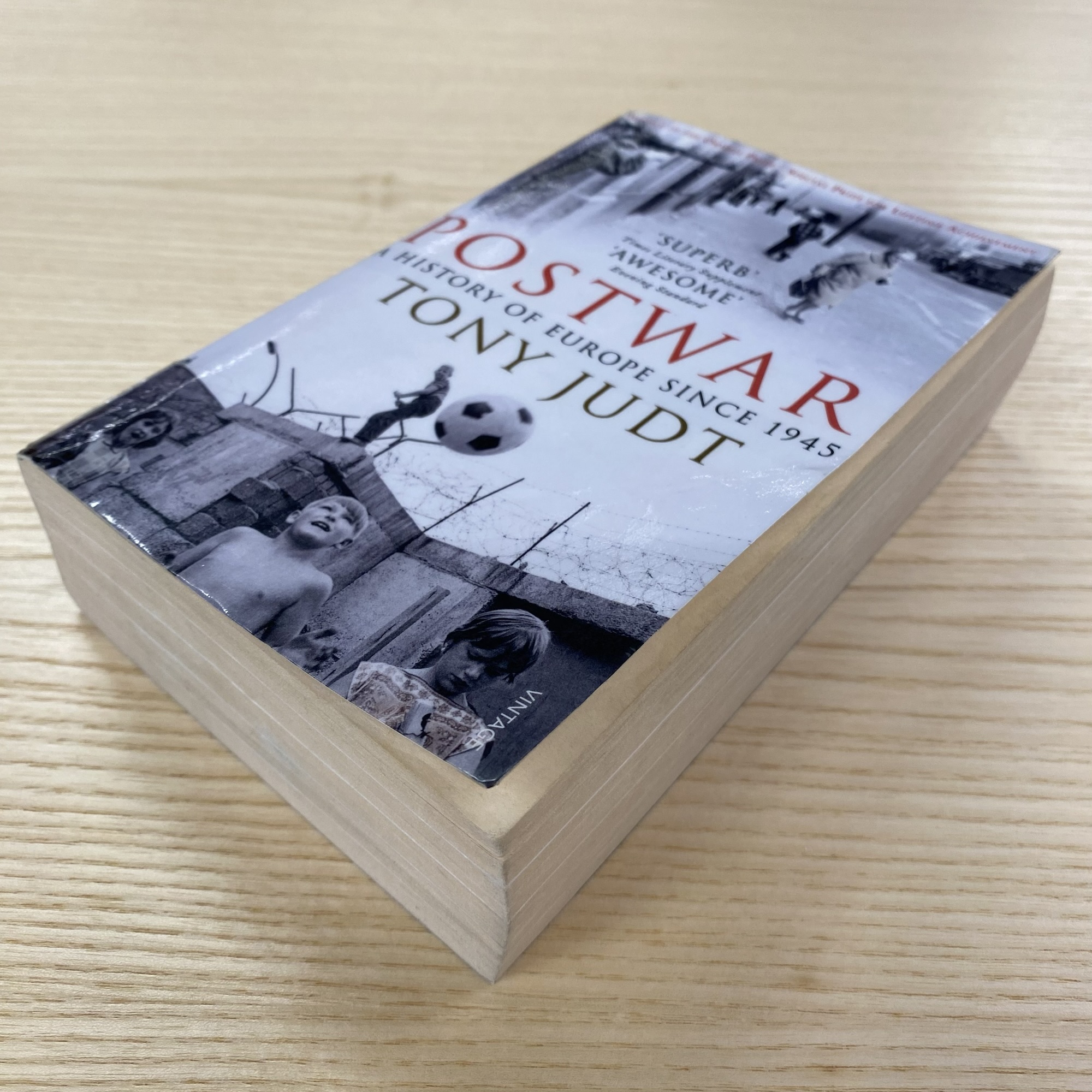 Tony Judt’s Postwar rests on a wooden table, with archival photographs surrounding the title A History of Europe Since 1945.